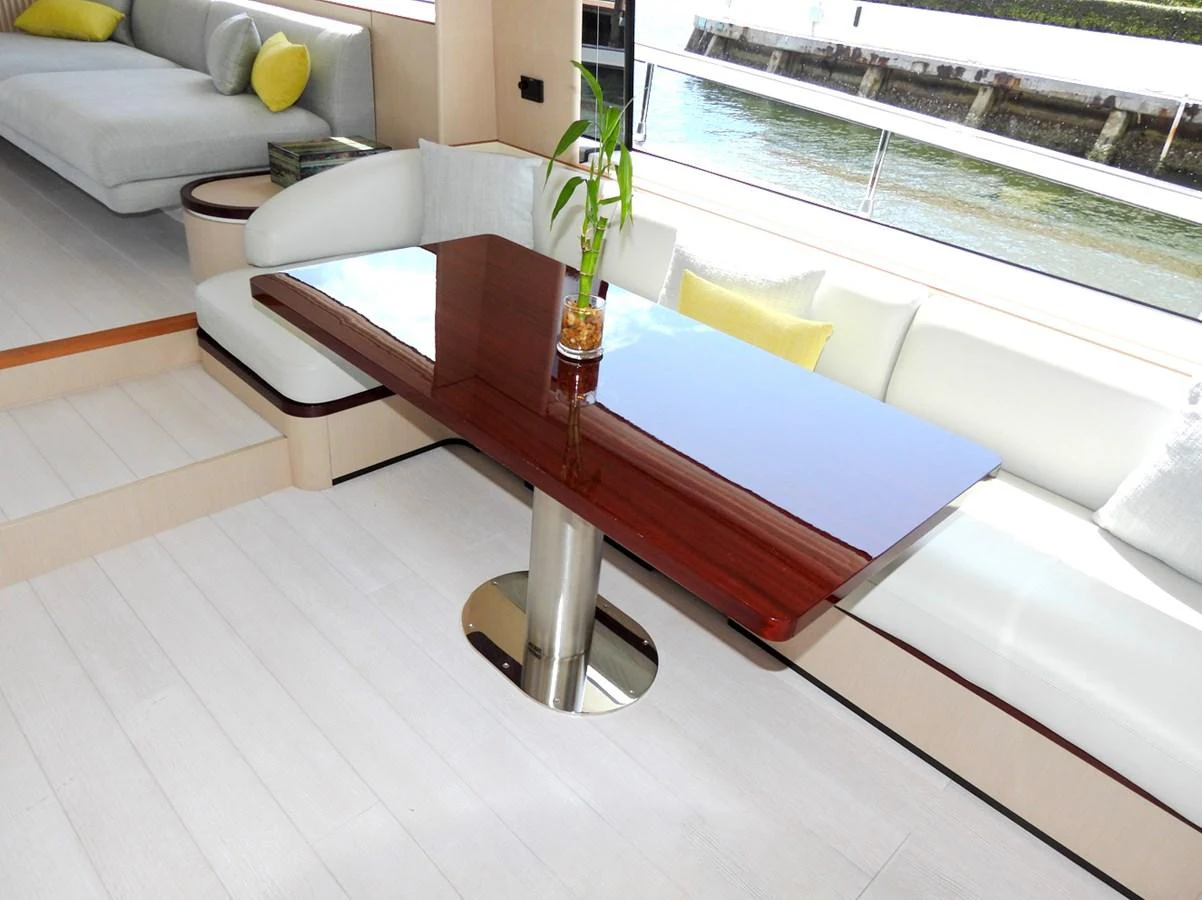 The saloon features a sleek dining area with a polished wooden table and comfortable seating, offering a serene view of the water. aboard EFFORTLESS Yacht for Sale