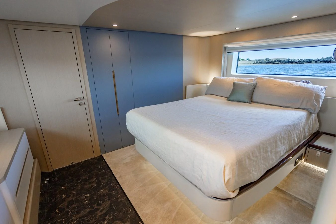 The stateroom features a comfortable bed with a scenic view through a large window. aboard EFFORTLESS Yacht for Sale
