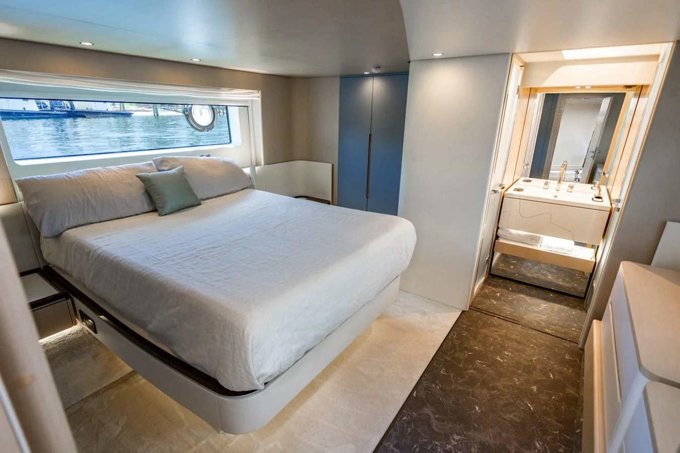The stateroom features a comfortable bed with a view of the water through a large window. aboard EFFORTLESS Yacht for Sale