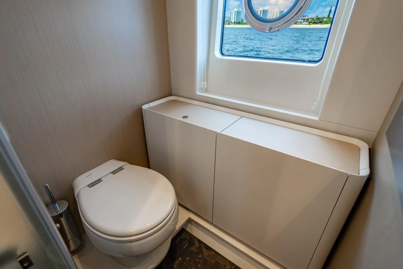 The yacht's head features a modern toilet and a window with a view of the water. aboard EFFORTLESS Yacht for Sale