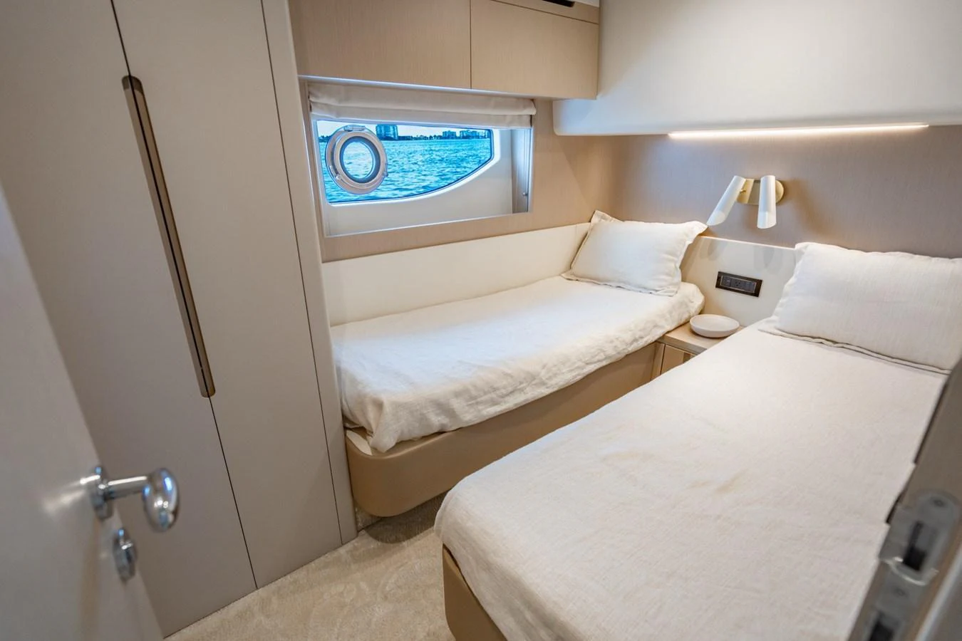 The guest cabin features twin beds with a serene view through the porthole. aboard EFFORTLESS Yacht for Sale