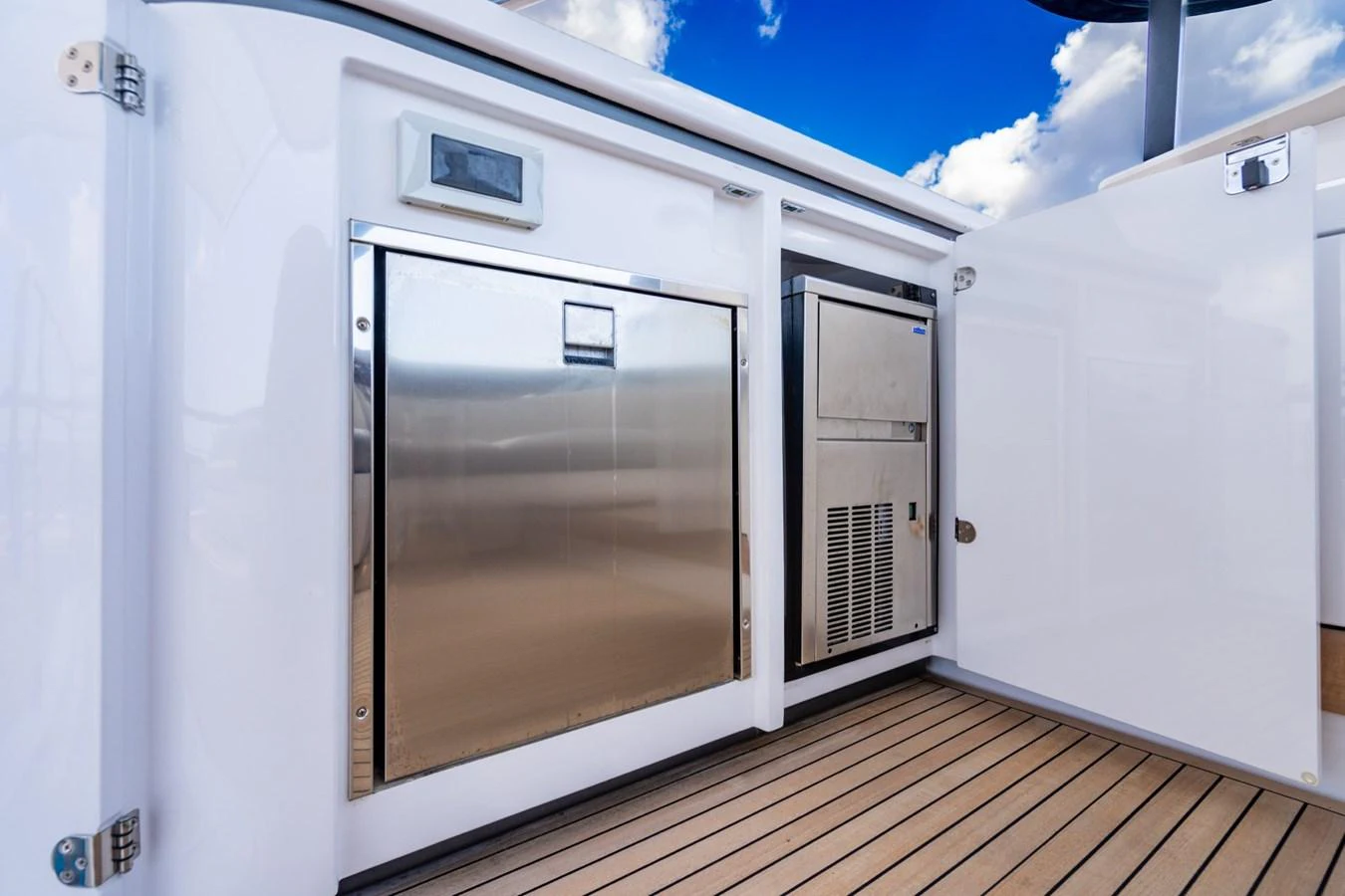 The image showcases a sleek, modern storage area on the yacht's deck with stainless steel appliances and white cabinetry. aboard EFFORTLESS Yacht for Sale