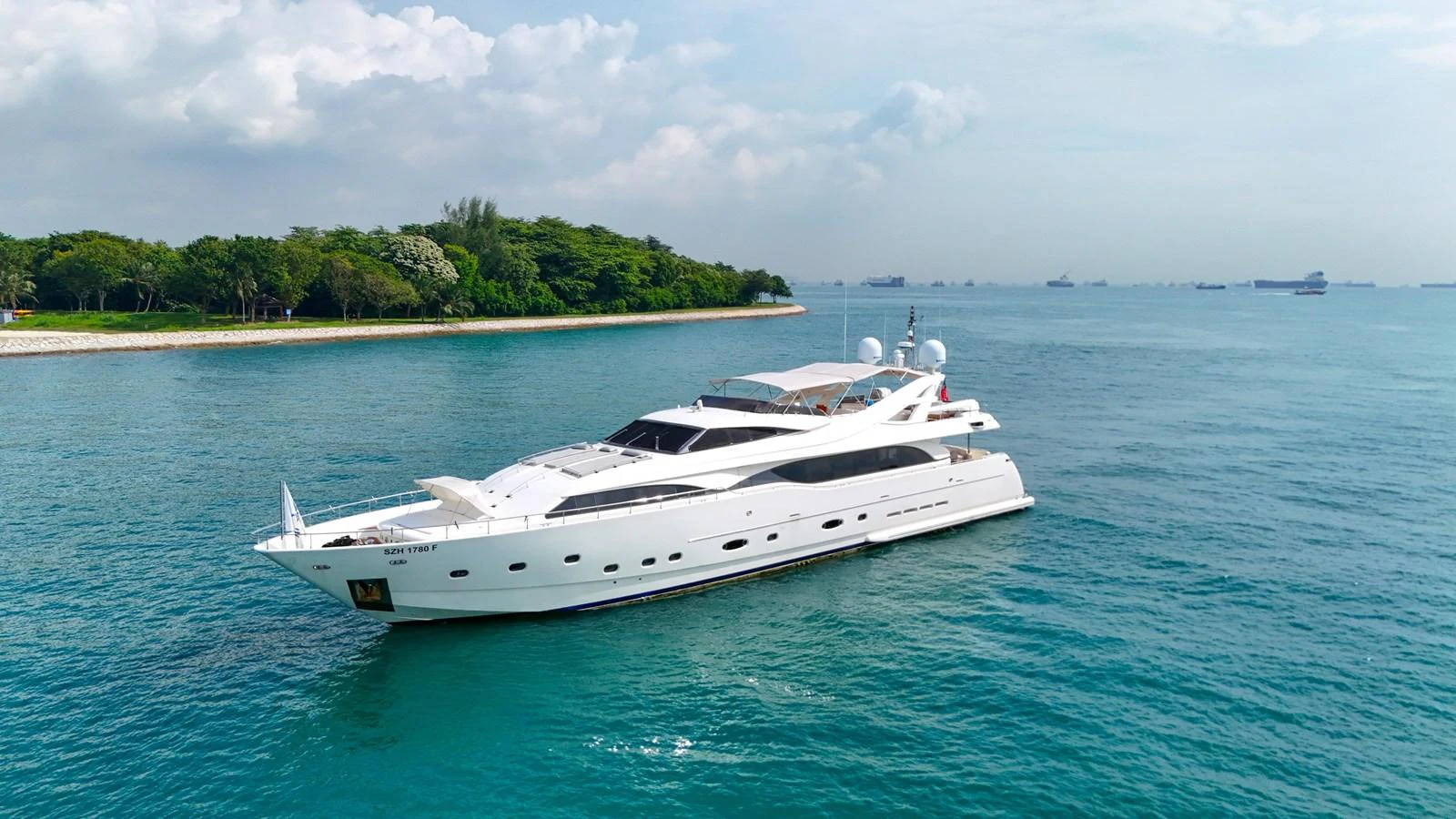 A sleek white yacht cruises gracefully on calm blue waters near a lush green shoreline. aboard CUSTOM LINE 112 Yacht for Sale