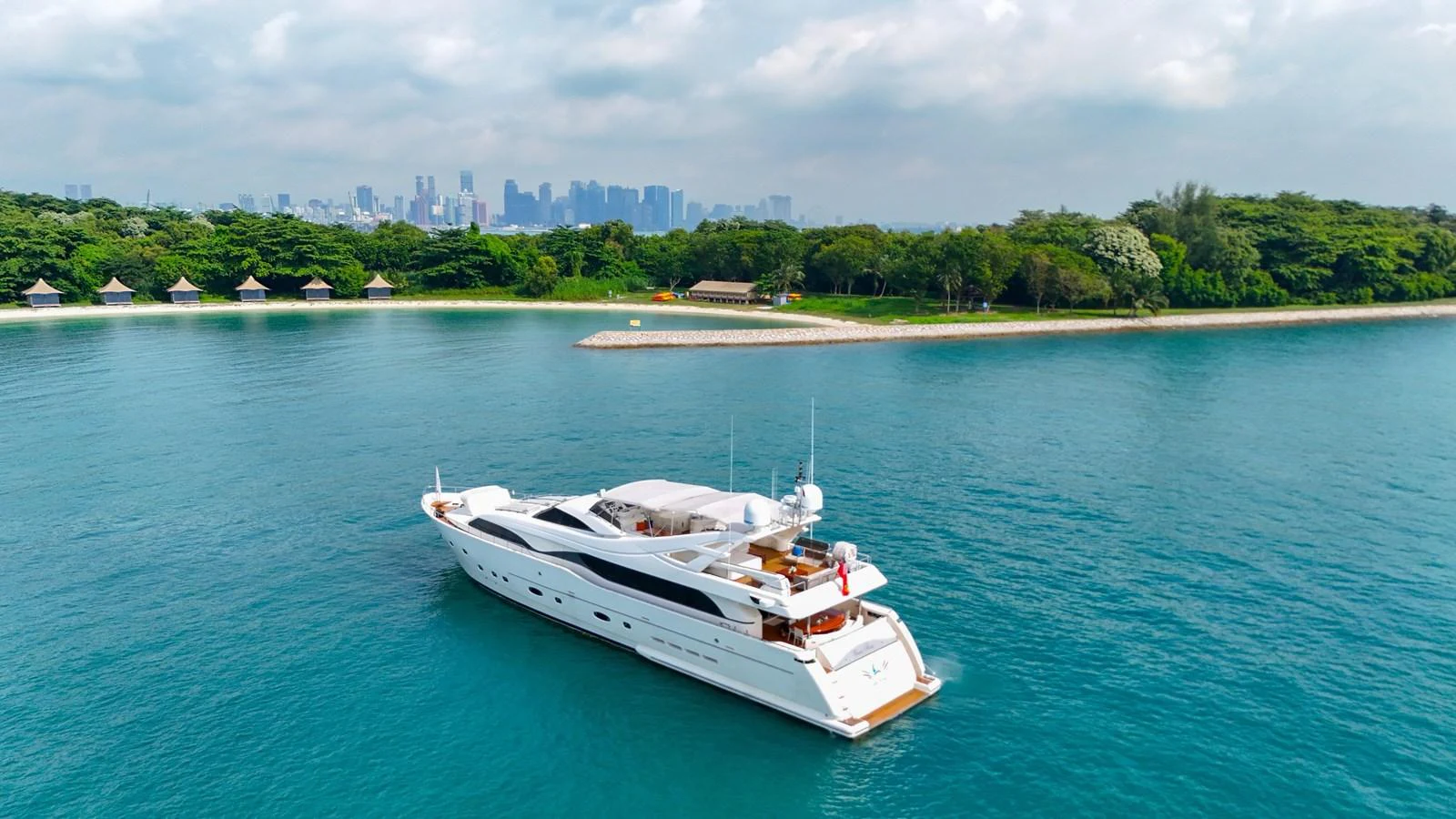 A sleek, modern yacht cruises near a lush, green shoreline with a distant city skyline. aboard CUSTOM LINE 112 Yacht for Sale