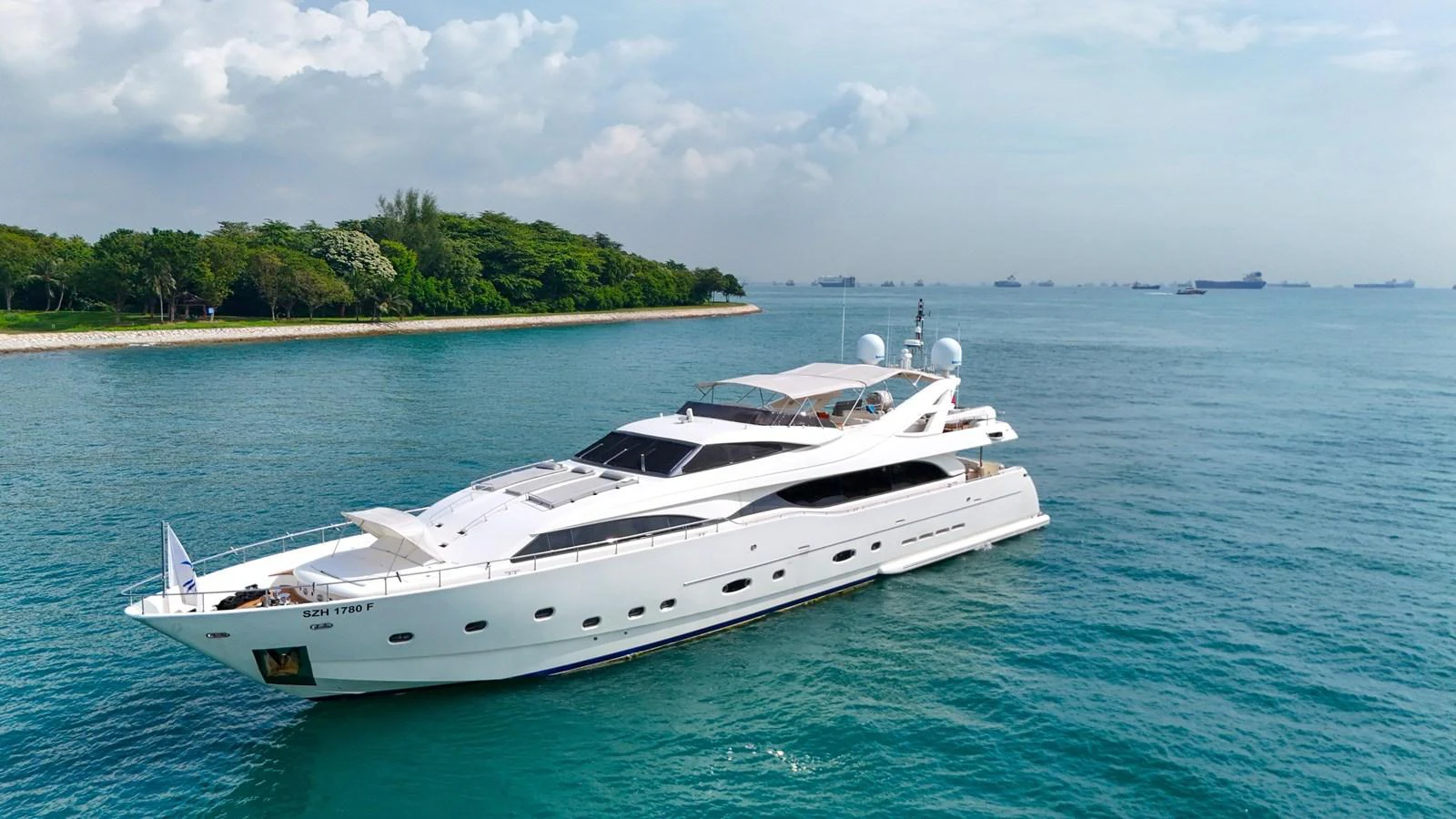 A sleek white yacht cruises gracefully on calm blue waters with a lush green shoreline in the background. aboard CUSTOM LINE 112 Yacht for Sale