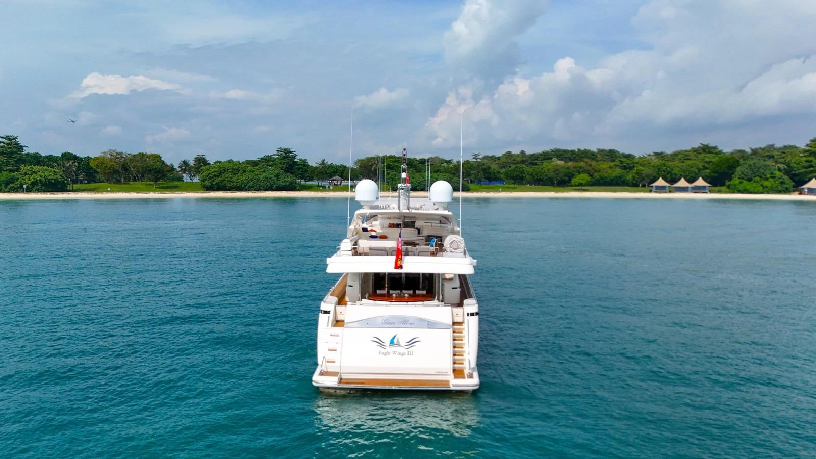A yacht is anchored near a serene coastline with lush greenery in the background. aboard CUSTOM LINE 112 Yacht for Sale