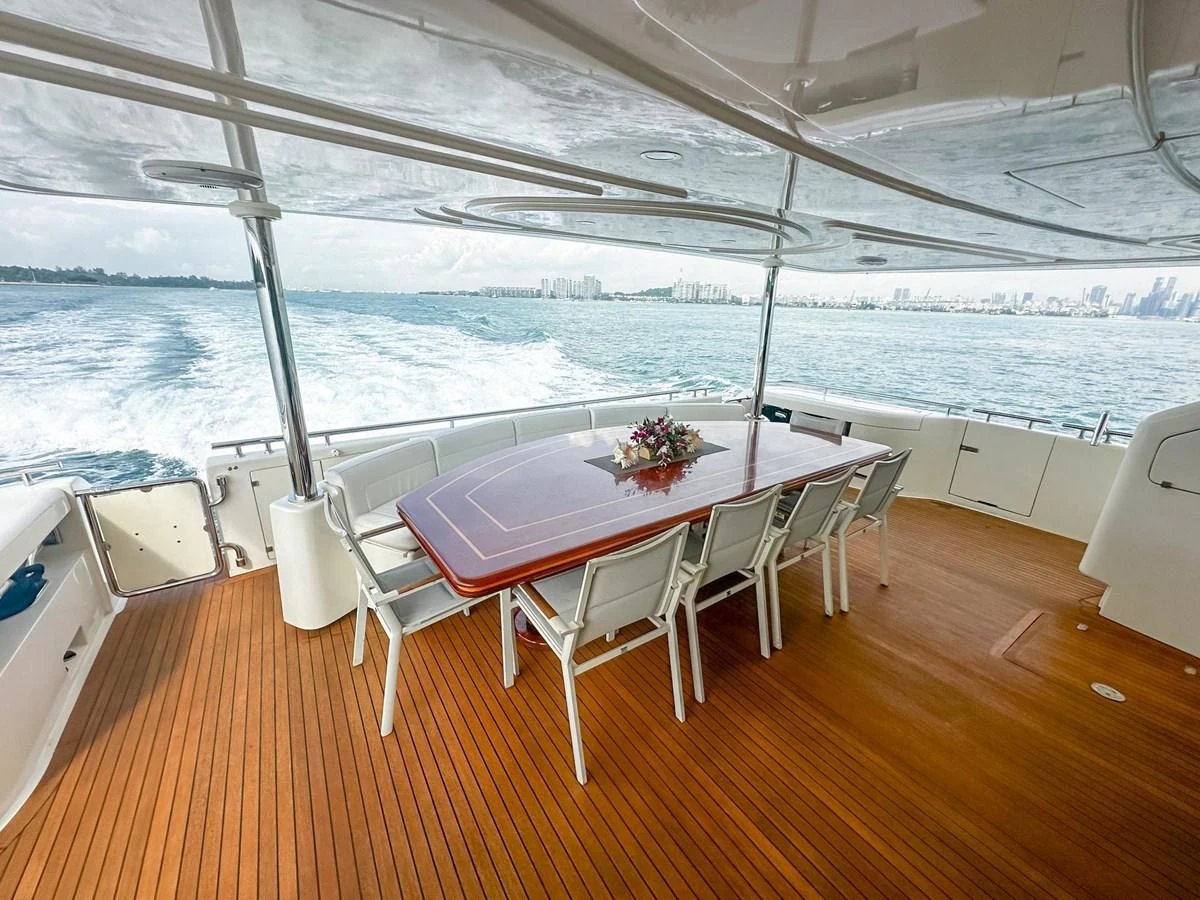 The aft deck features a spacious dining area with a beautiful wooden table and comfortable seating, perfect for enjoying meals with a view. aboard CUSTOM LINE 112 Yacht for Sale