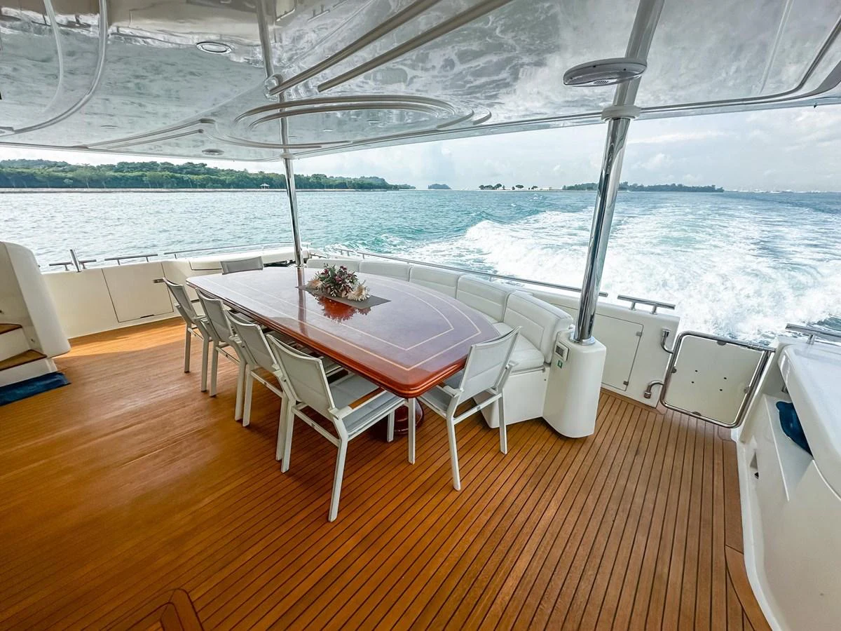 The aft deck features a spacious dining area with a polished wooden table and comfortable seating, perfect for alfresco meals with a view. aboard CUSTOM LINE 112 Yacht for Sale