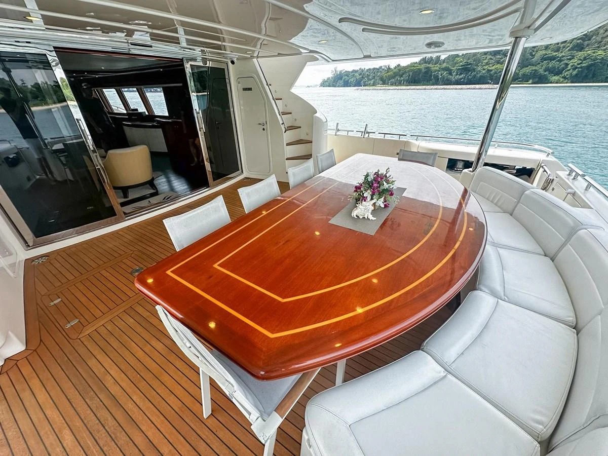 The aft deck features an elegant dining area with a polished wooden table and comfortable seating, perfect for alfresco meals with a view. aboard CUSTOM LINE 112 Yacht for Sale