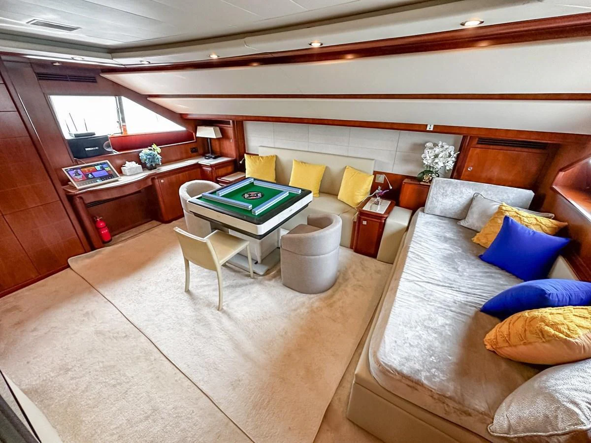 The yacht's lounge area features a comfortable seating arrangement with a card table, perfect for relaxation and entertainment. aboard CUSTOM LINE 112 Yacht for Sale