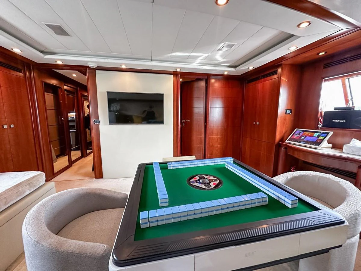 The yacht's interior features a luxurious game room with a mahjong table and plush seating. aboard CUSTOM LINE 112 Yacht for Sale