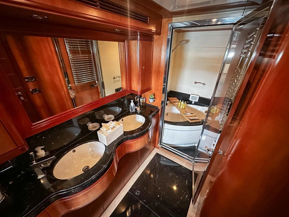 The yacht's bathroom features elegant wood paneling and a sleek black countertop with dual sinks. aboard CUSTOM LINE 112 Yacht for Sale