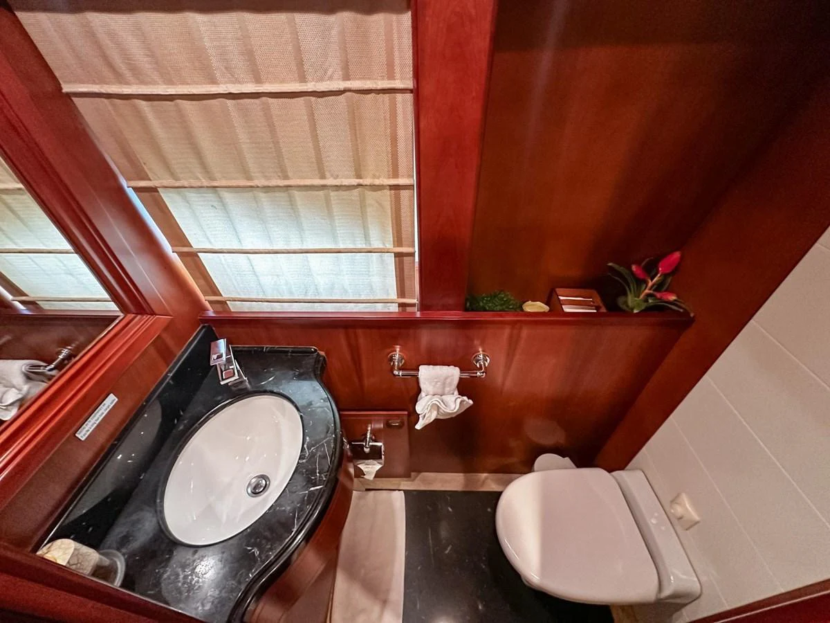 The yacht's bathroom features elegant wood paneling and a sleek black countertop. aboard CUSTOM LINE 112 Yacht for Sale