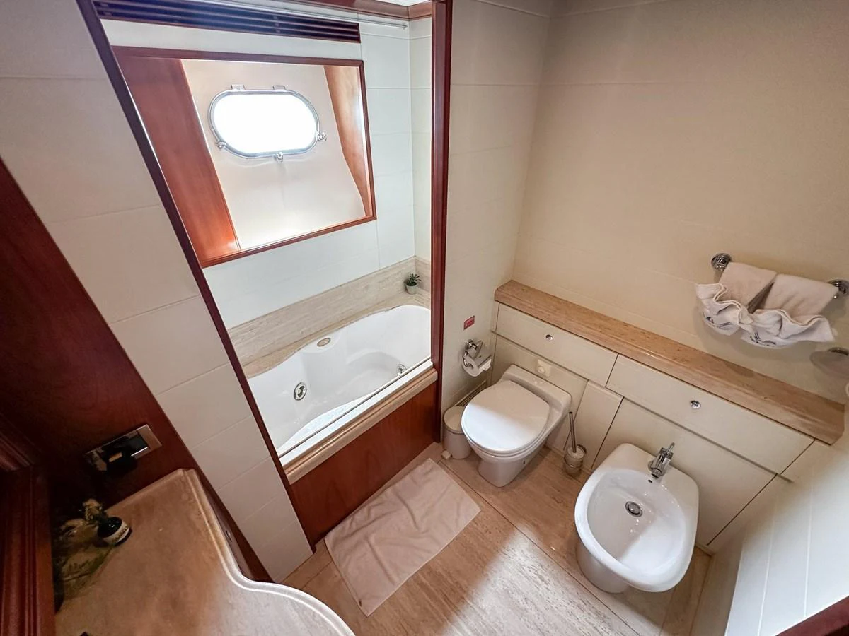 The yacht's bathroom features a bathtub, toilet, bidet, and sink in a well-lit space. aboard CUSTOM LINE 112 Yacht for Sale