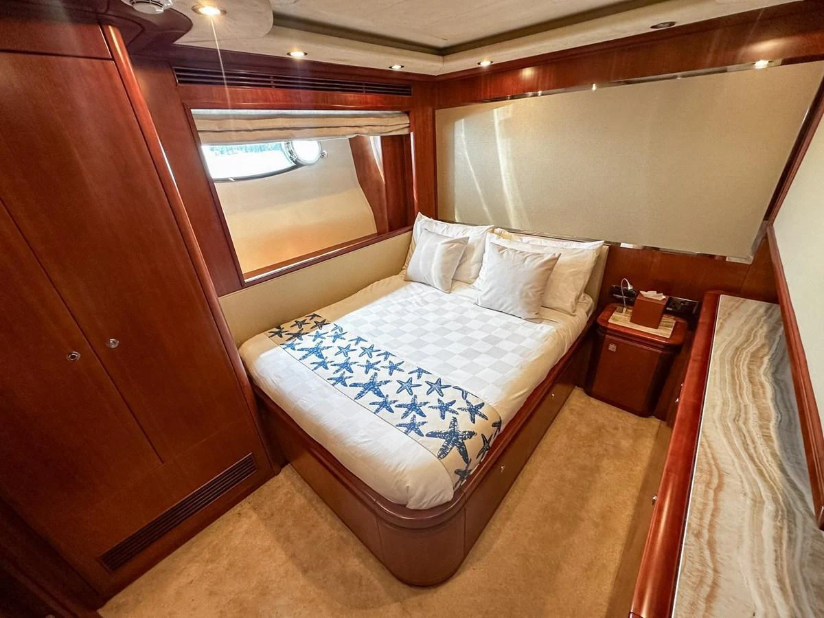 A cozy guest stateroom featuring a comfortable bed with elegant bedding and warm wood finishes. aboard CUSTOM LINE 112 Yacht for Sale