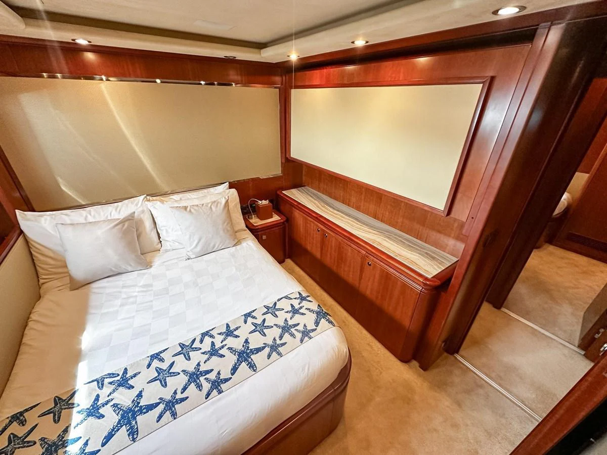A cozy stateroom featuring a comfortable bed with starfish-themed bedding and warm wooden accents. aboard CUSTOM LINE 112 Yacht for Sale
