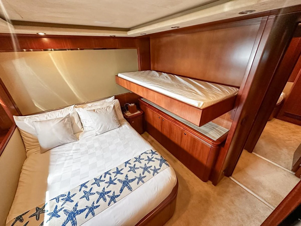 A cozy guest stateroom featuring a double bed and an overhead bunk, adorned with elegant wooden finishes. aboard CUSTOM LINE 112 Yacht for Sale