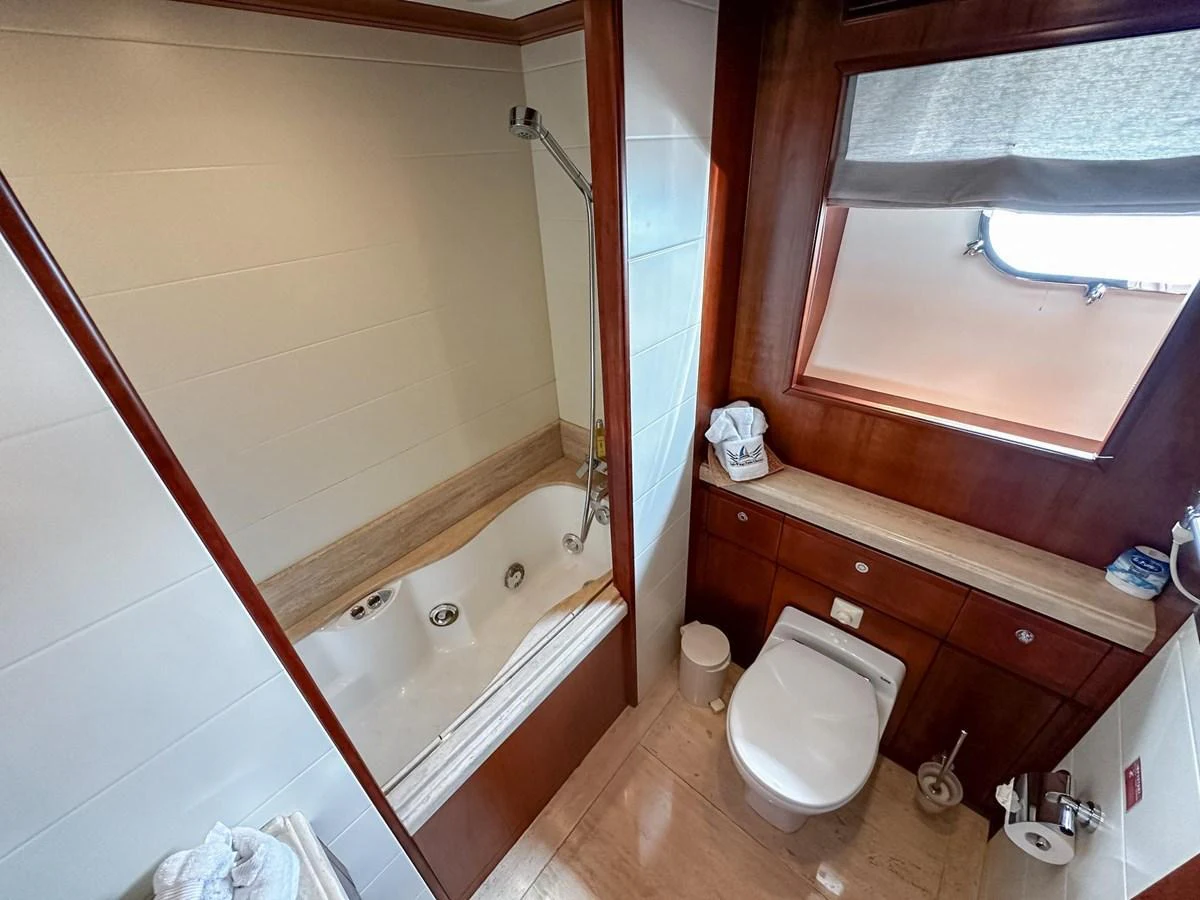 The yacht's bathroom features a luxurious bathtub and a well-appointed toilet area with wooden accents. aboard CUSTOM LINE 112 Yacht for Sale