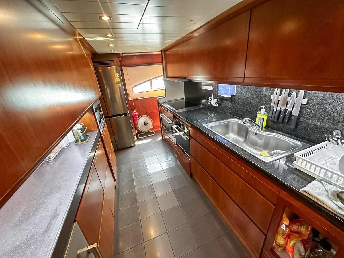 The galley features sleek wooden cabinetry, modern appliances, and ample counter space for gourmet meal preparation. aboard CUSTOM LINE 112 Yacht for Sale