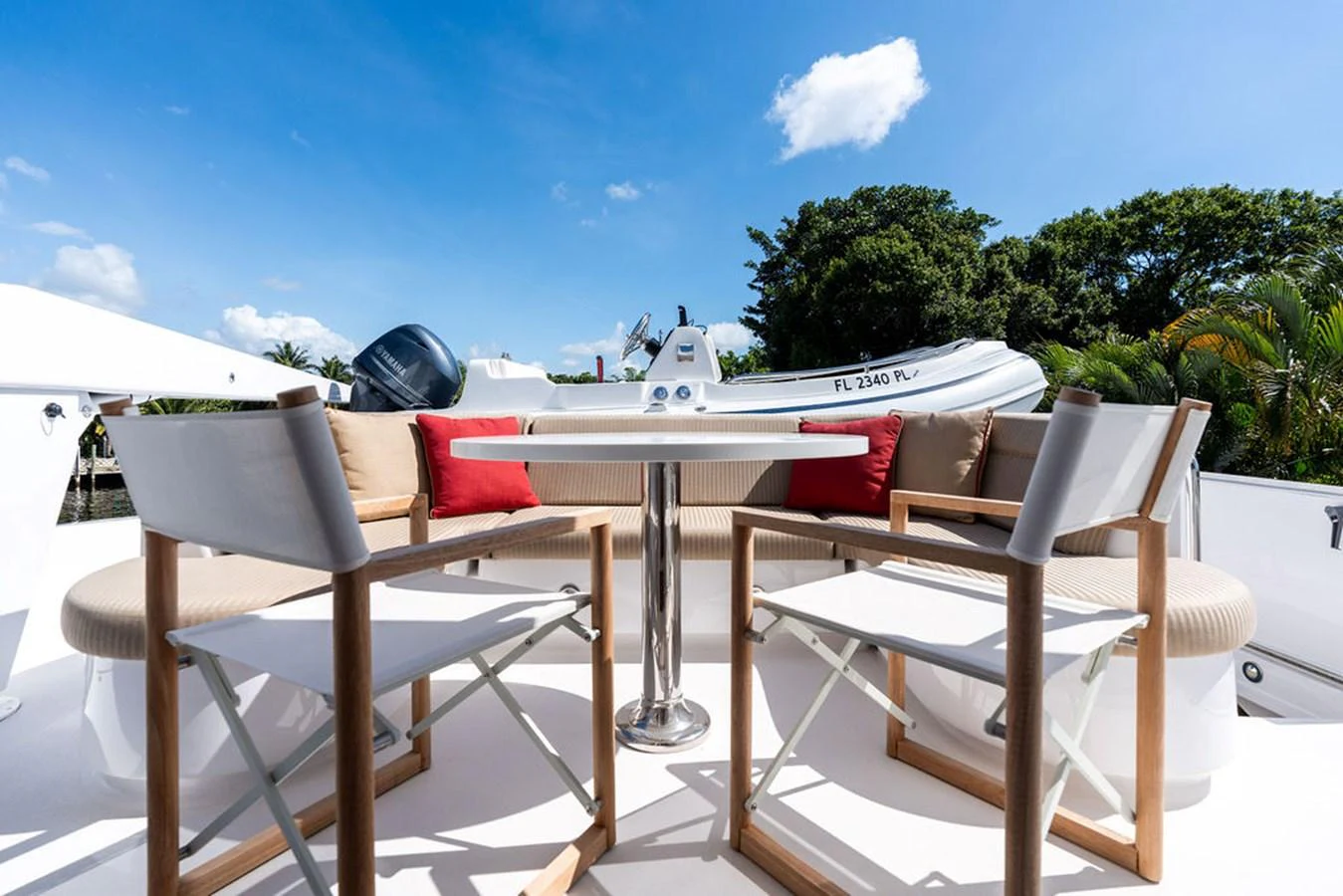The sundeck features a stylish seating area with a table, surrounded by comfortable chairs and accented with red cushions. aboard GRIFFIN Yacht for Sale