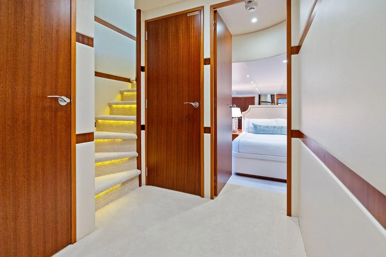 A luxurious interior hallway with wooden doors and a staircase leading to a well-lit room. aboard GRIFFIN Yacht for Sale