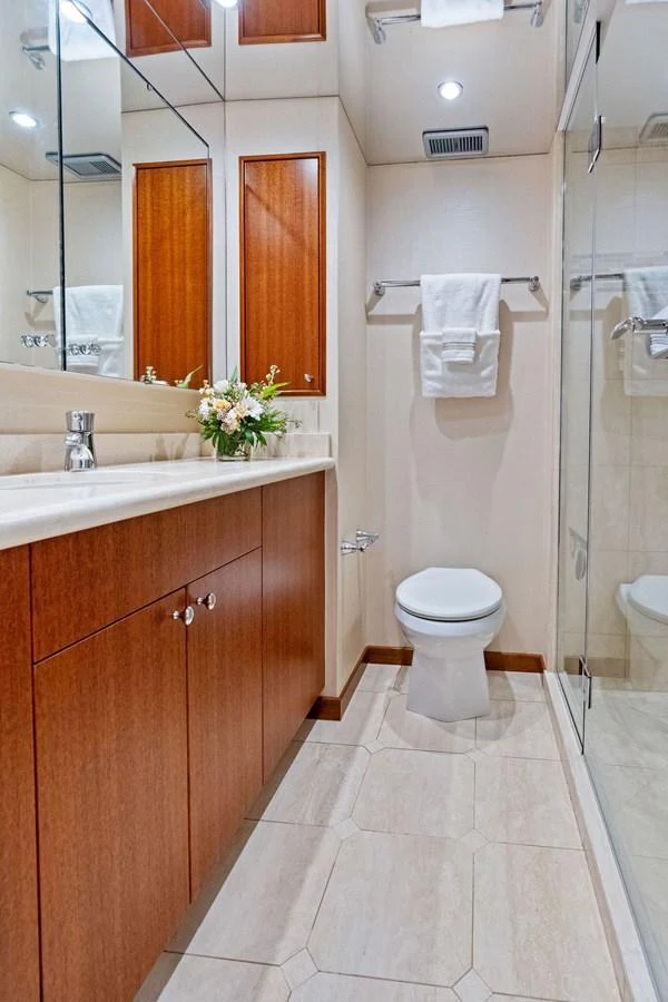 The yacht's bathroom features elegant wooden cabinetry, a pristine white toilet, and a spacious glass shower. aboard GRIFFIN Yacht for Sale