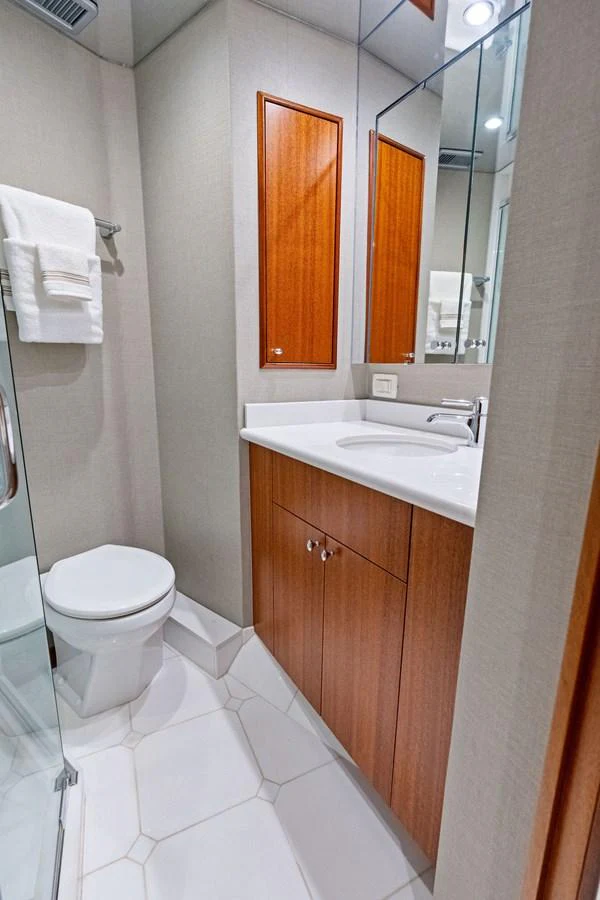 A sleek and modern yacht bathroom featuring a glass shower, wooden cabinetry, and elegant fixtures. aboard GRIFFIN Yacht for Sale