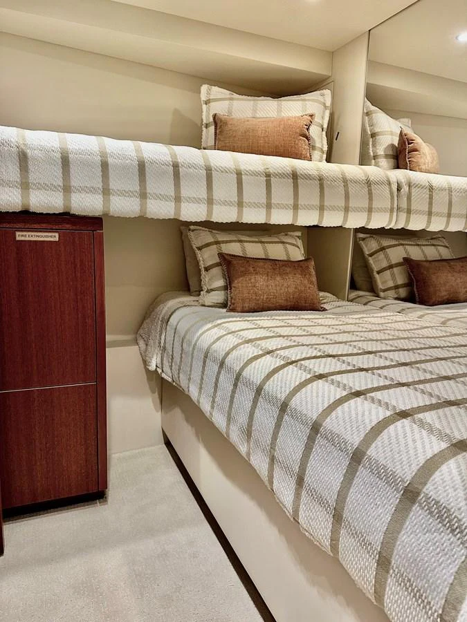 The guest cabin features cozy bunk beds with striped bedding and warm-toned pillows. aboard GRIFFIN Yacht for Sale