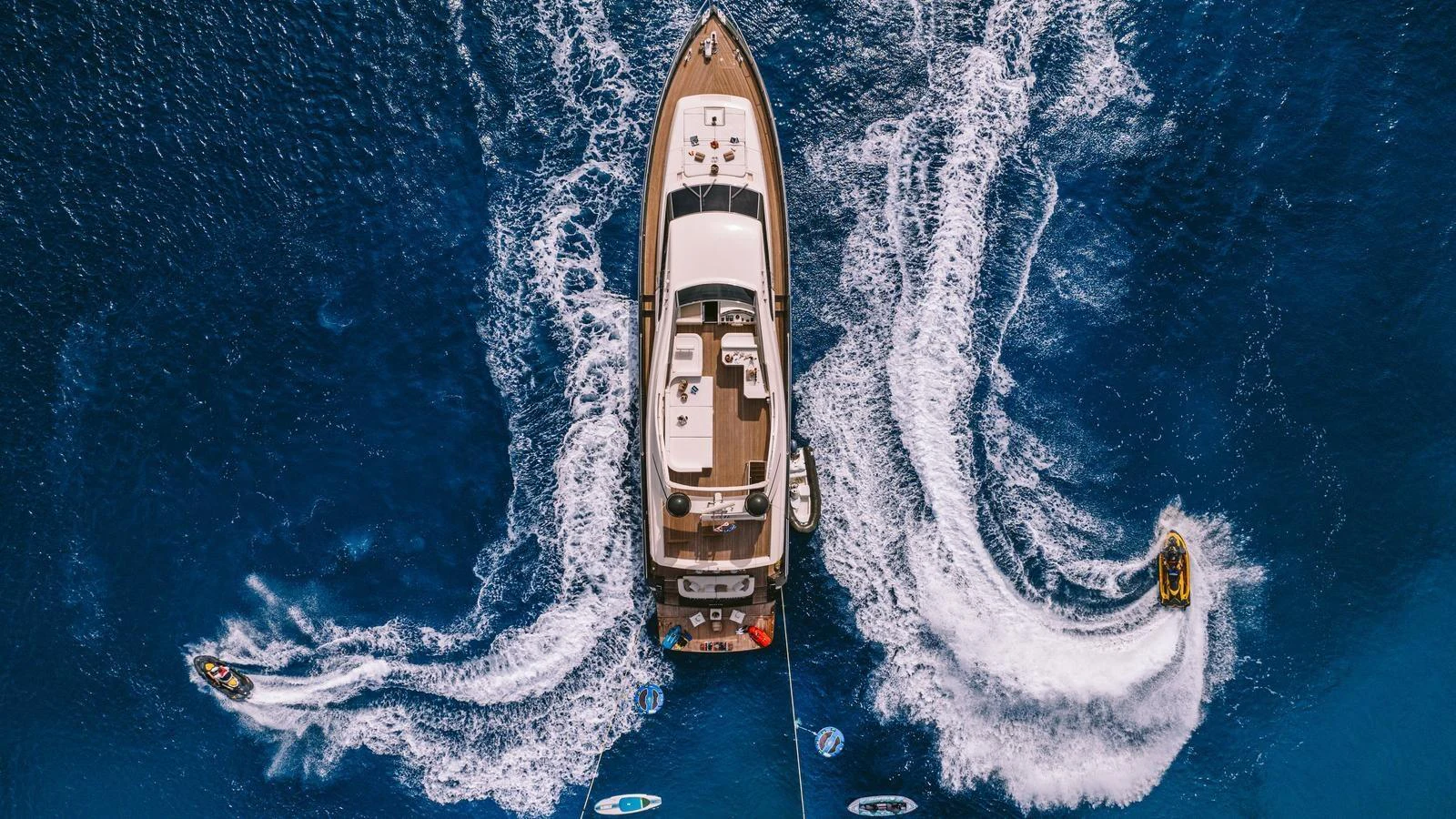 Aerial view of a yacht cruising through vibrant blue waters, surrounded by water toys. aboard THIS IS MINE Yacht for Sale