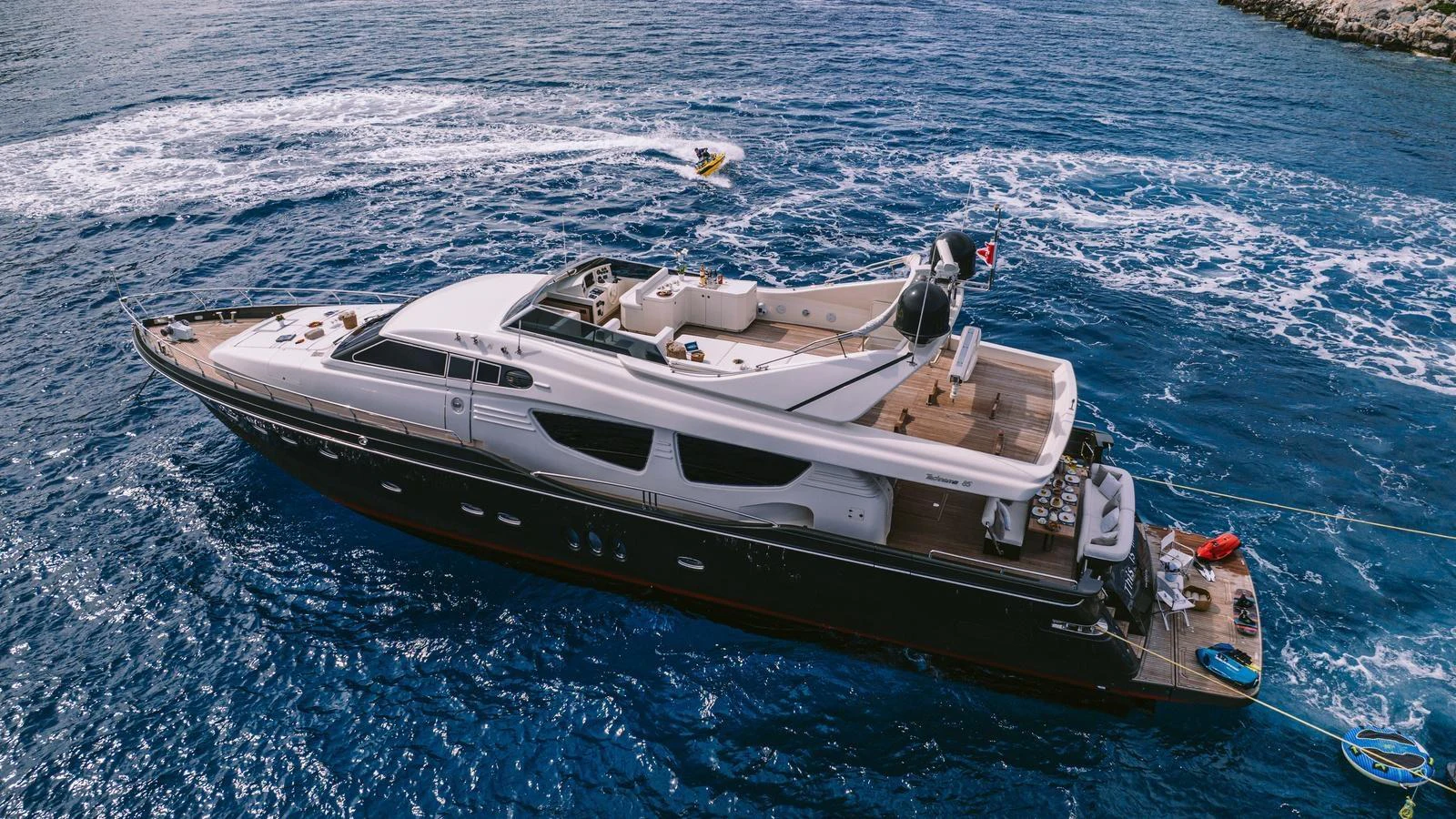 A sleek yacht cruises through vibrant blue waters, showcasing its luxurious design. aboard THIS IS MINE Yacht for Sale