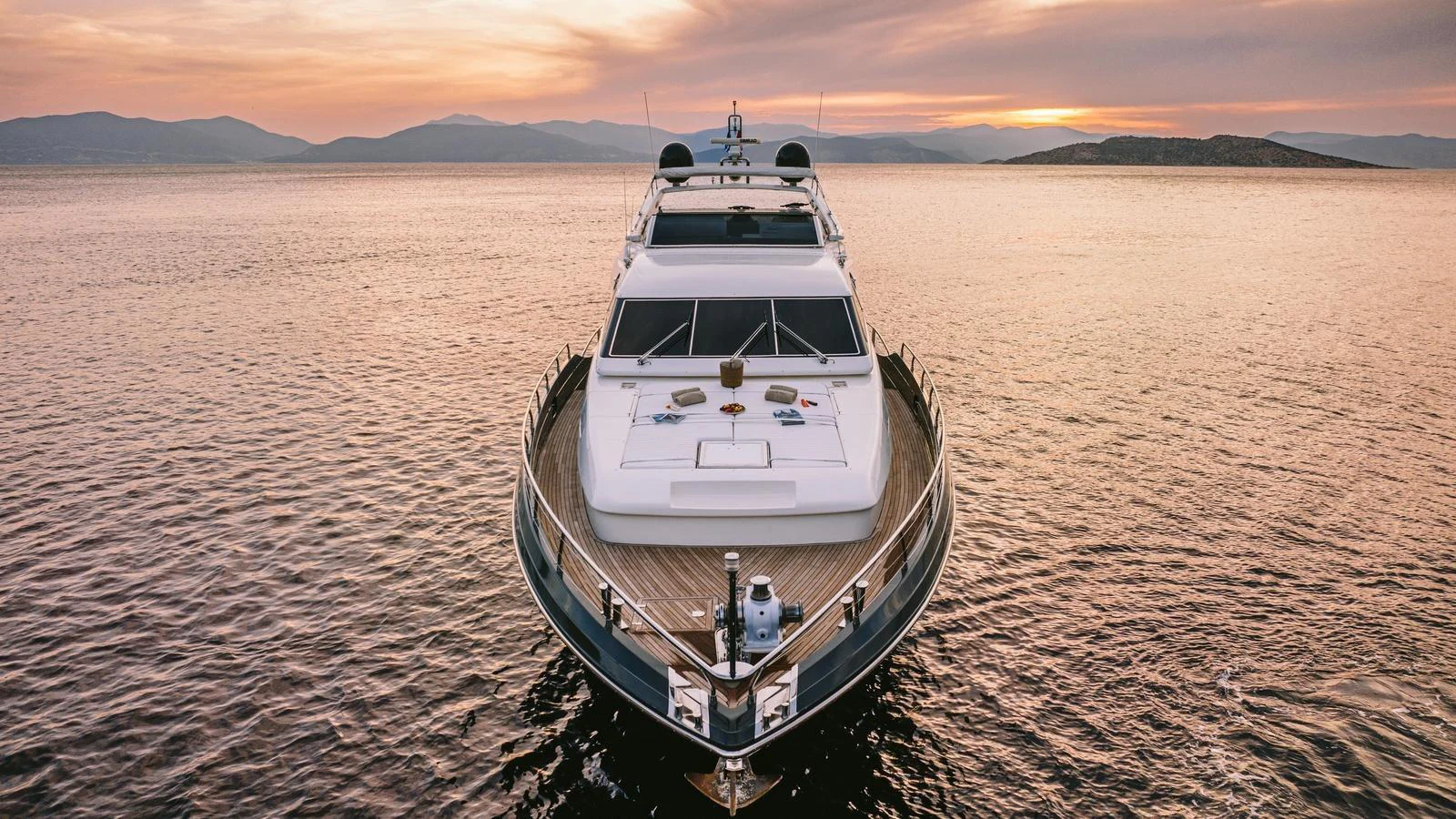 A luxurious yacht is anchored on calm waters during a beautiful sunset. aboard THIS IS MINE Yacht for Sale