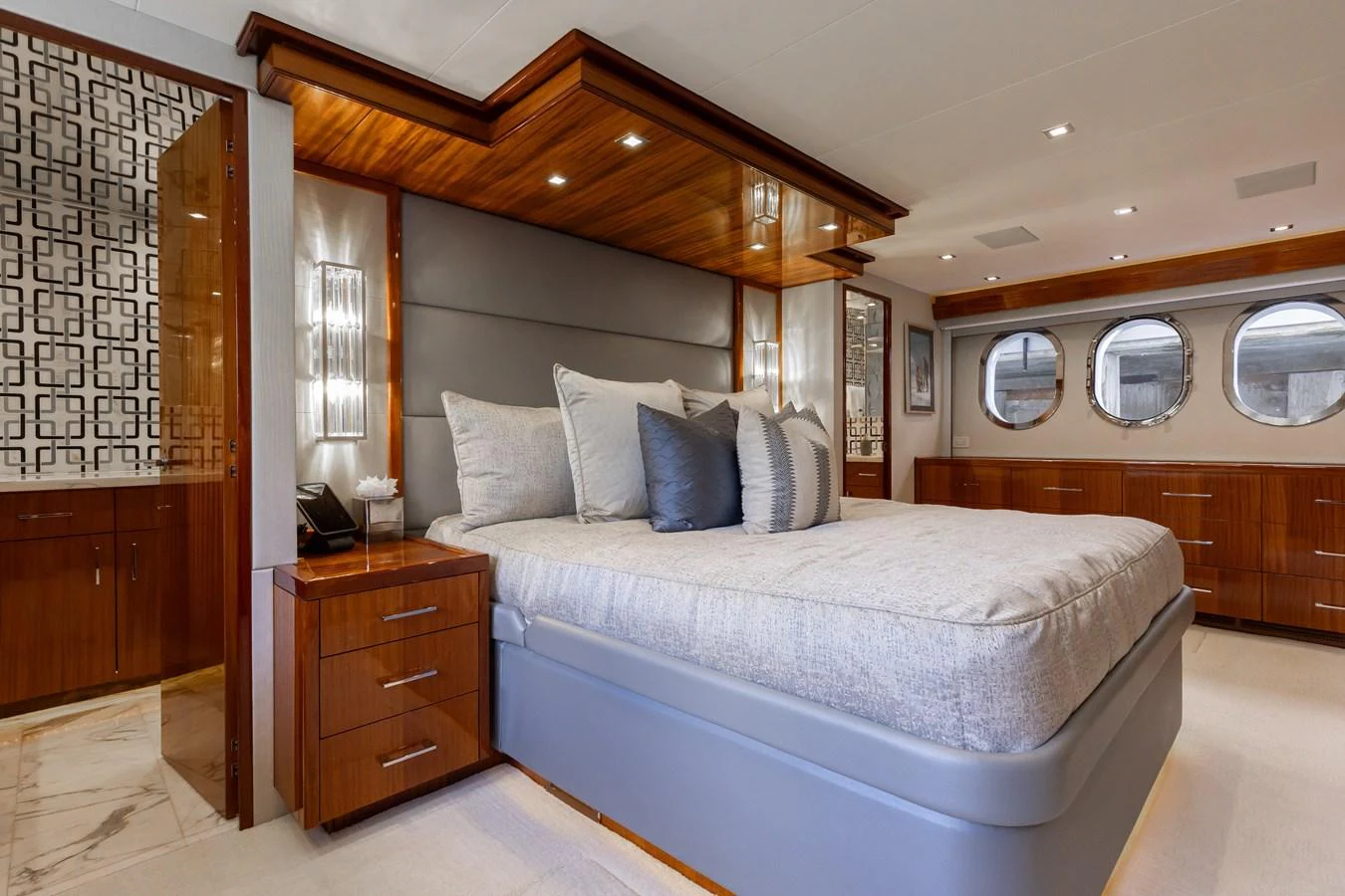 The master stateroom features a luxurious bed with elegant wood finishes and ample natural light from the porthole windows. aboard RITZ SEA Yacht for Sale