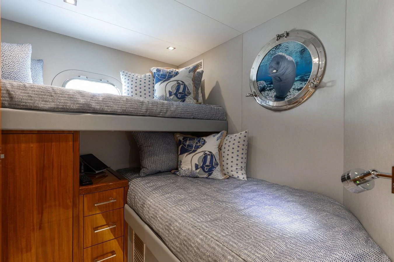 The cozy guest cabin features bunk beds with nautical-themed decor and a porthole window. aboard RITZ SEA Yacht for Sale