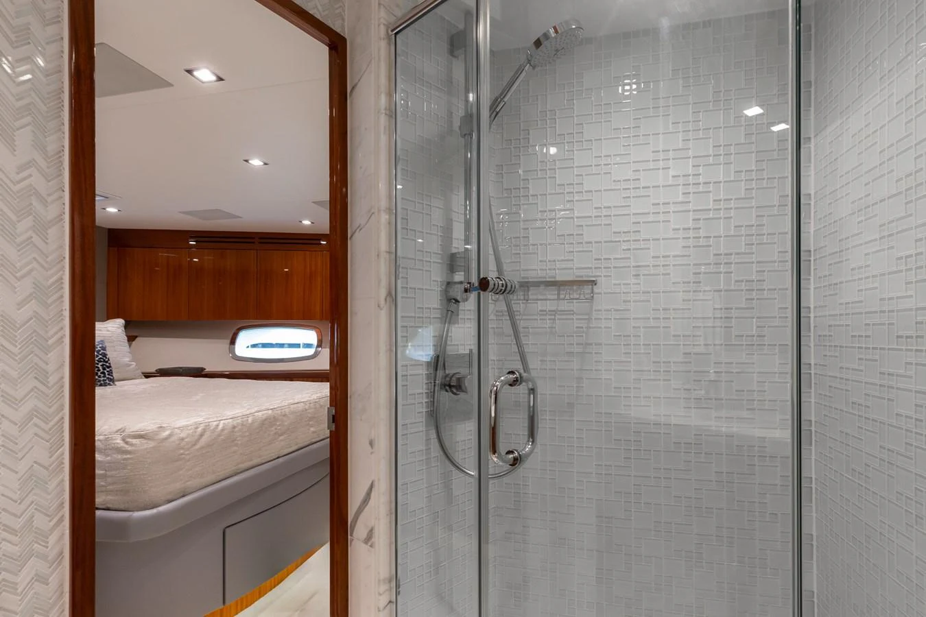 The yacht's bathroom features a modern glass-enclosed shower with a glimpse into a cozy stateroom. aboard RITZ SEA Yacht for Sale