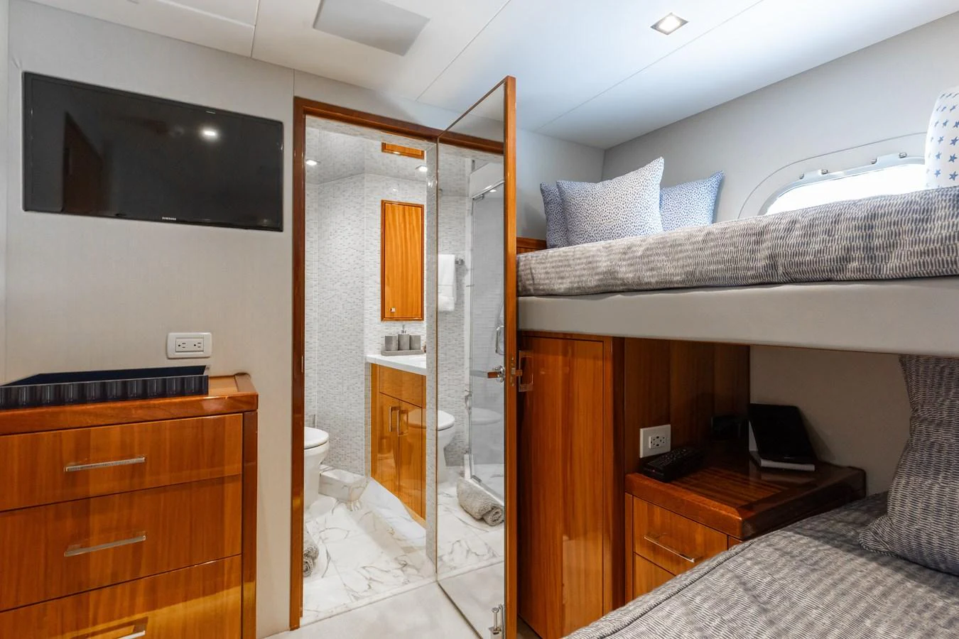 A cozy cabin with bunk beds and an ensuite bathroom, featuring elegant wood finishes and modern amenities. aboard RITZ SEA Yacht for Sale