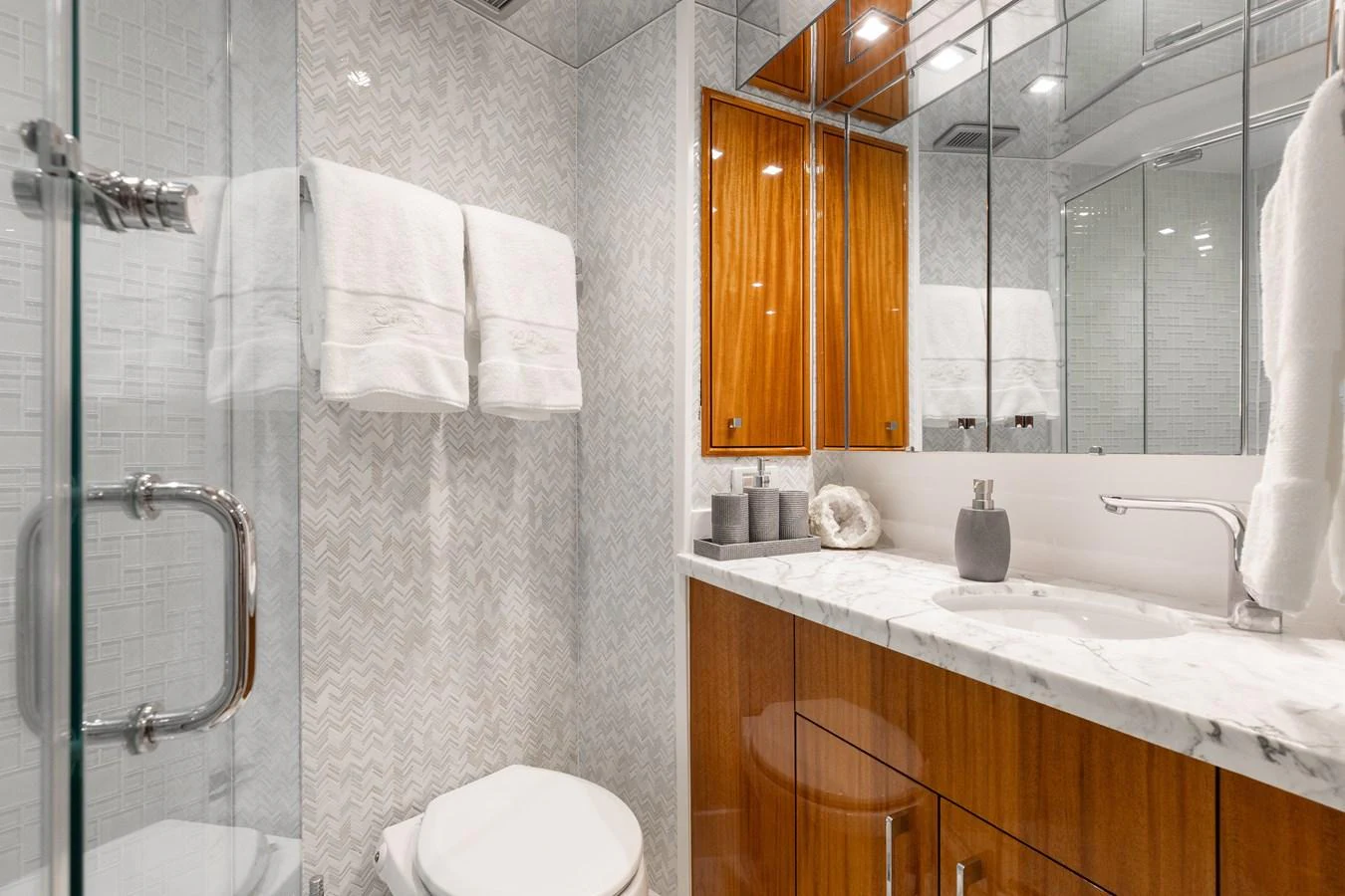 The yacht's bathroom features elegant wood cabinetry, a marble countertop, and a glass-enclosed shower. aboard RITZ SEA Yacht for Sale