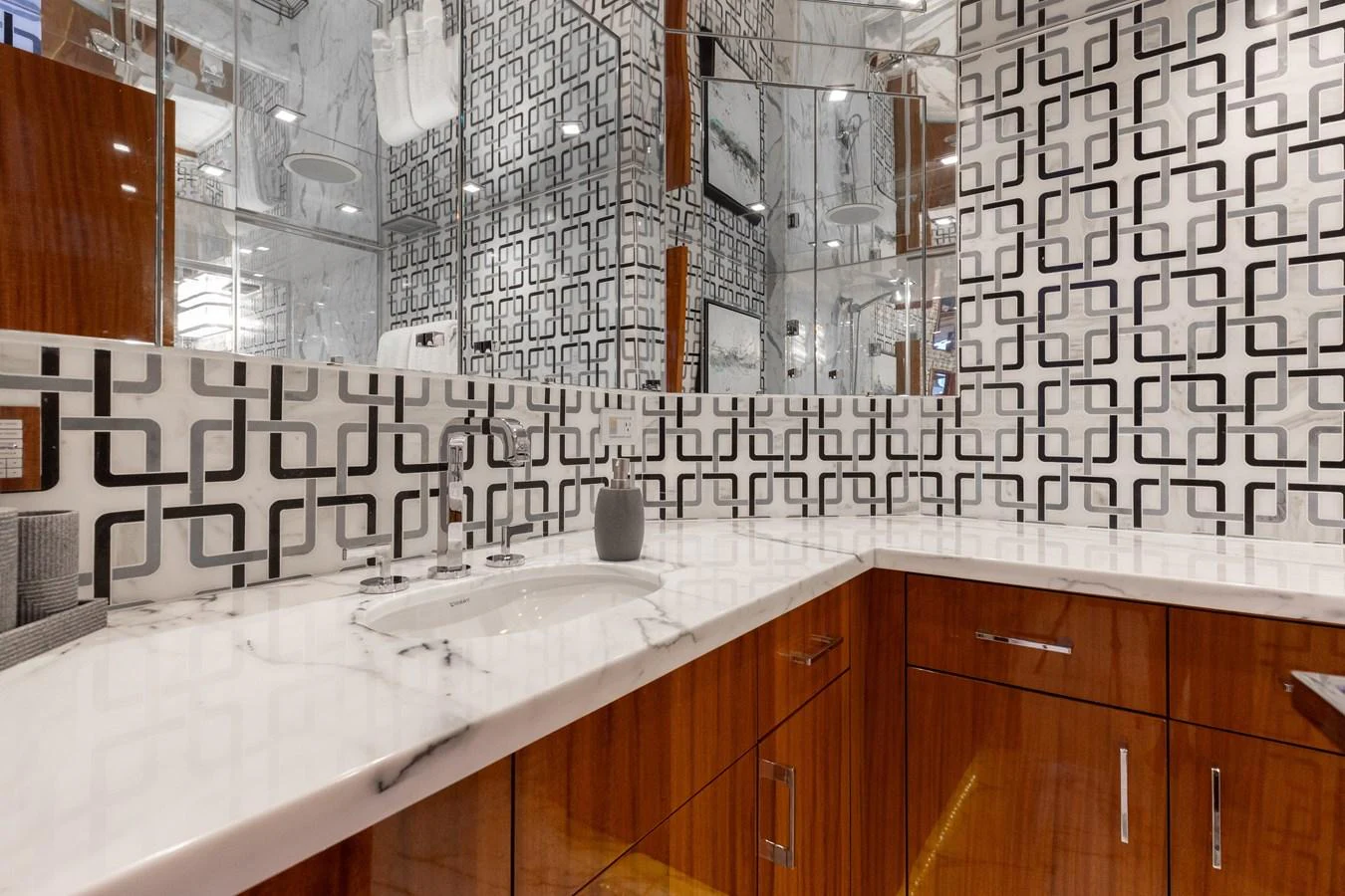 The bathroom features a modern design with geometric patterned walls and sleek wooden cabinetry. aboard RITZ SEA Yacht for Sale