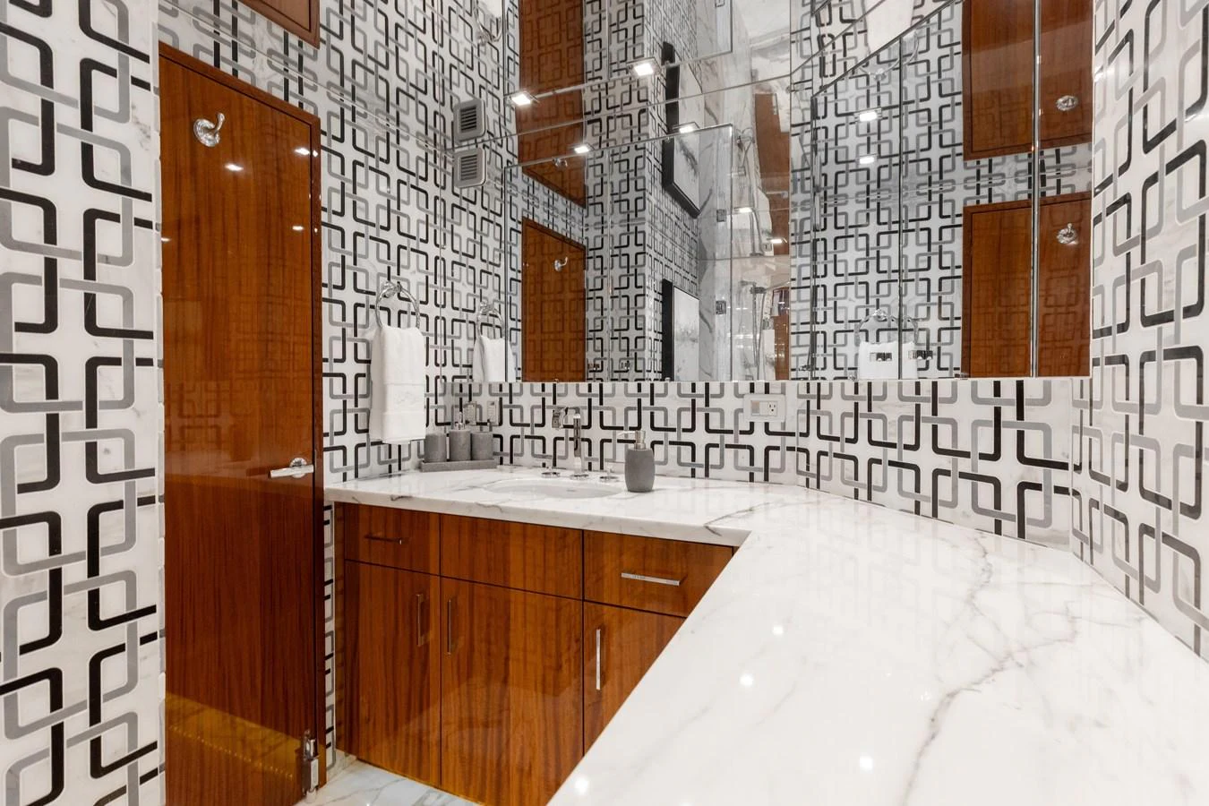 The bathroom features a modern design with geometric patterned walls and sleek wooden cabinetry. aboard RITZ SEA Yacht for Sale
