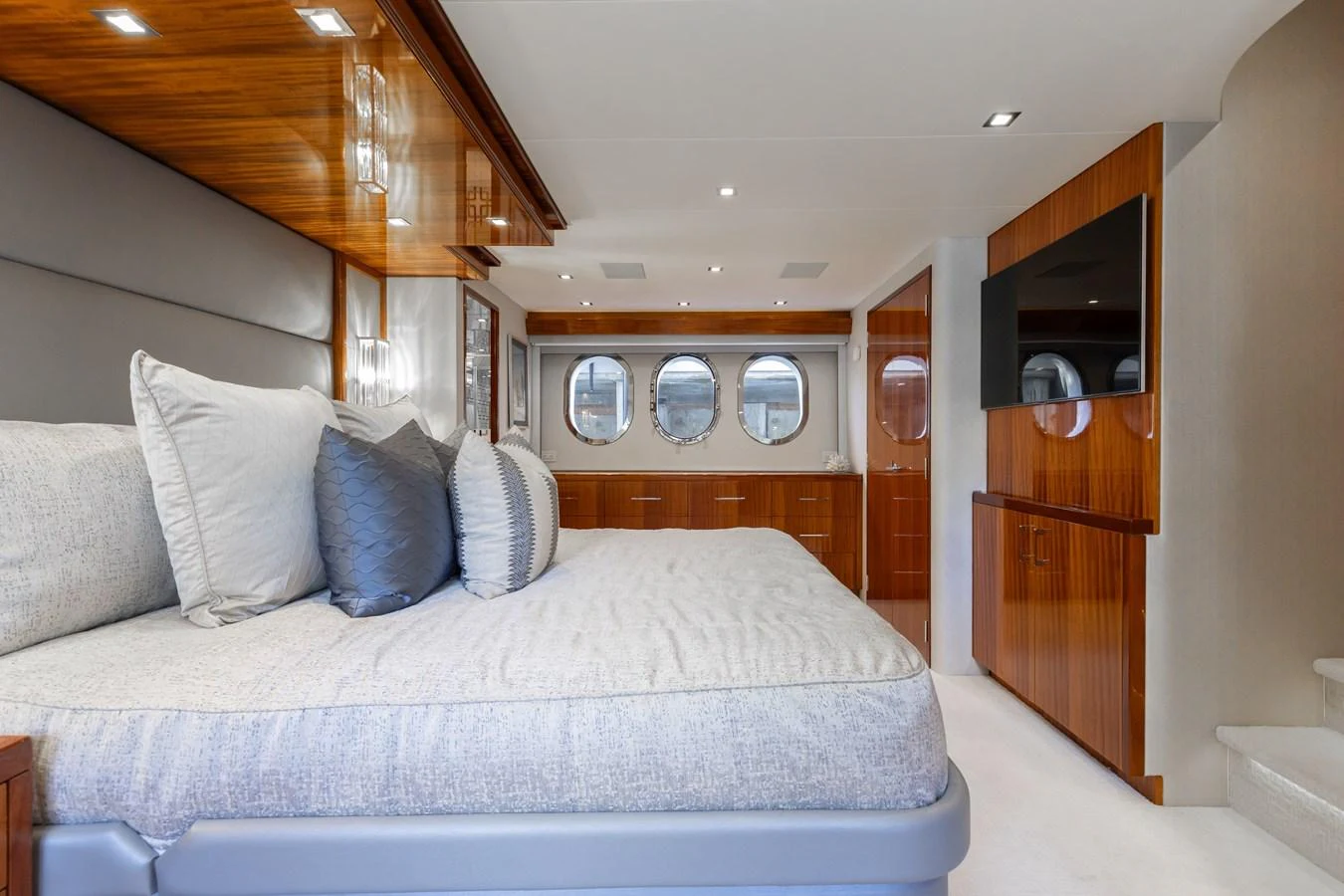 The master stateroom features a spacious bed, elegant wood finishes, and ample natural light from the porthole windows. aboard RITZ SEA Yacht for Sale