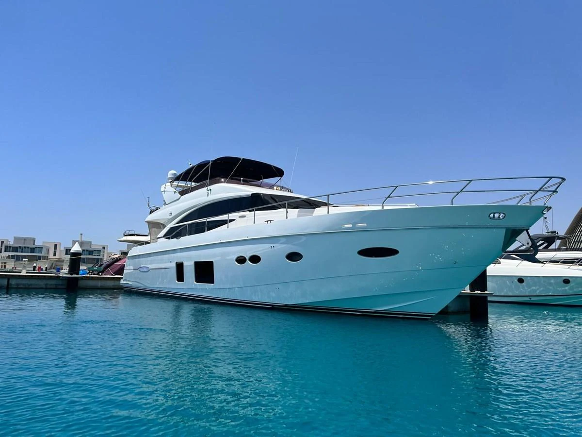 A sleek and modern yacht docked in a serene marina under a clear blue sky. aboard KAZZA Yacht for Sale