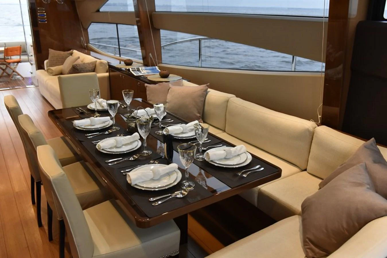 The yacht's dining area features a beautifully set table with elegant tableware and comfortable seating, offering a luxurious dining experience with a view of the sea. aboard KAZZA Yacht for Sale
