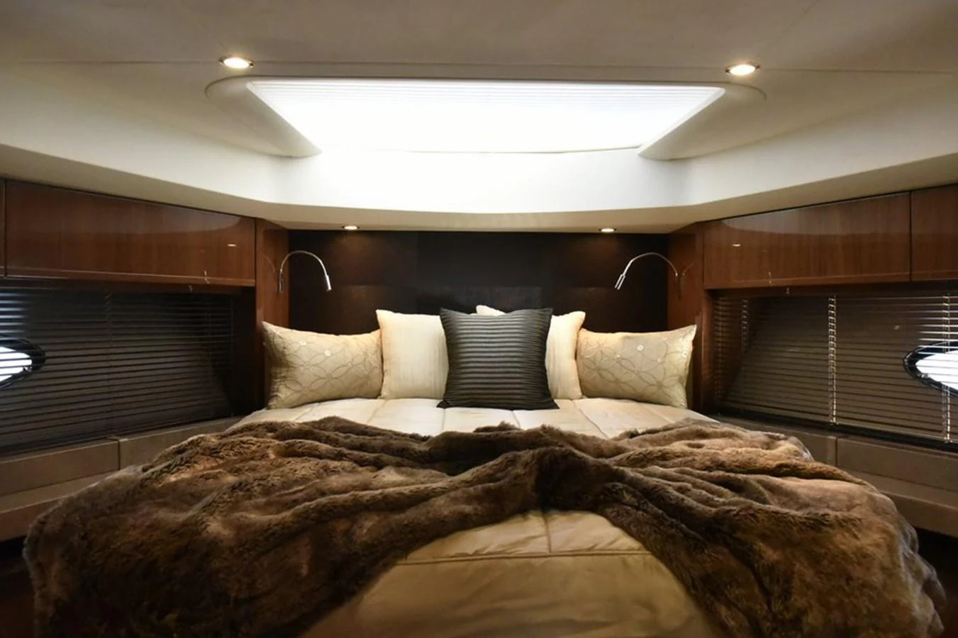 The master stateroom features a luxurious bed with plush pillows and a cozy blanket, illuminated by soft lighting. aboard KAZZA Yacht for Sale