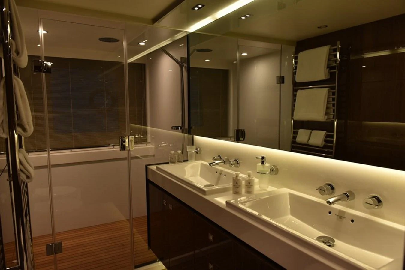 The yacht's bathroom features a double sink vanity and a spacious glass-enclosed shower. aboard KAZZA Yacht for Sale