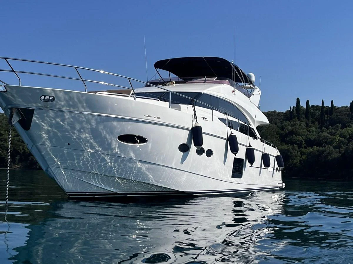A sleek white yacht glides through calm waters on a sunny day. aboard KAZZA Yacht for Sale
