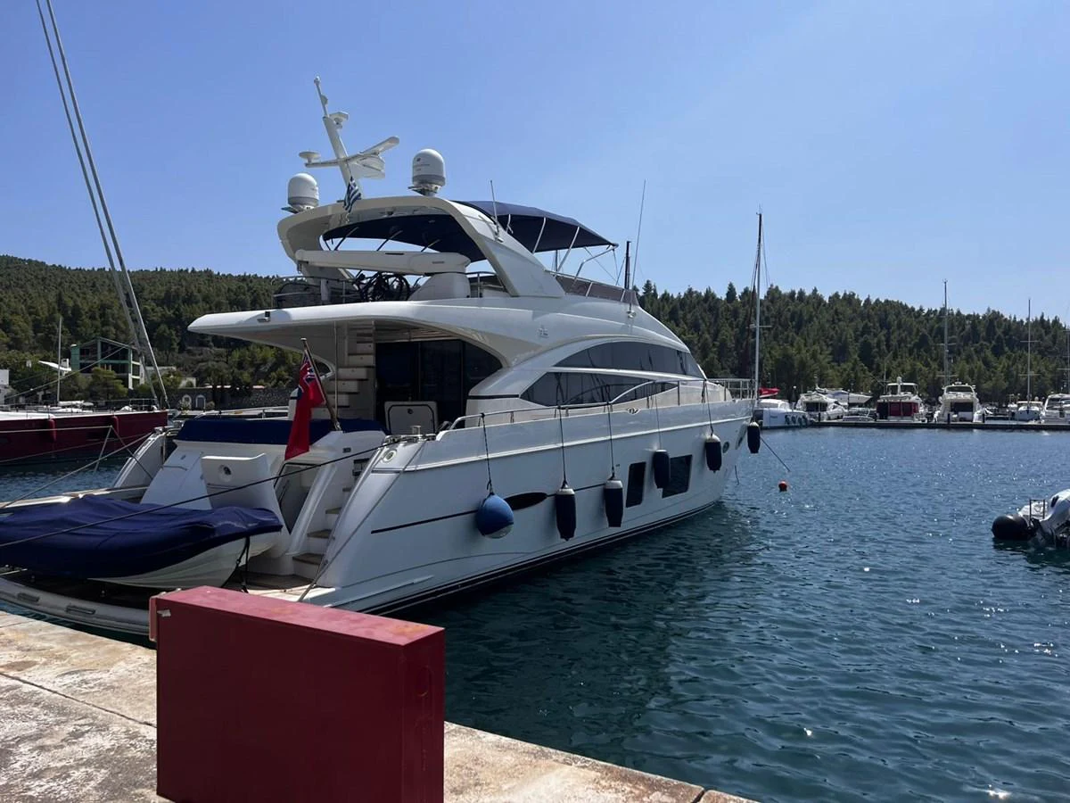 A sleek white yacht is docked at a marina, showcasing its elegant design and spacious deck areas. aboard KAZZA Yacht for Sale