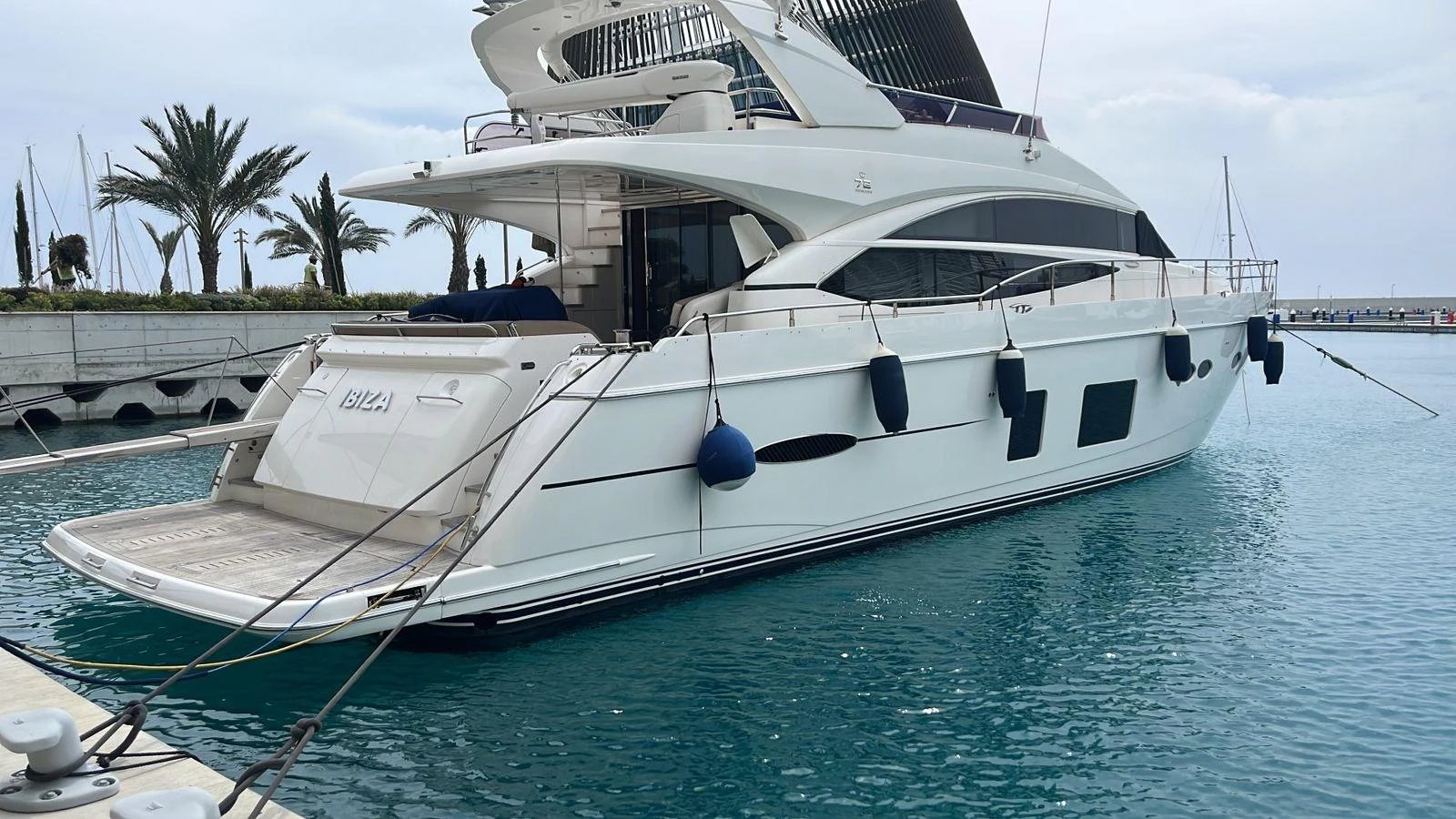 A sleek and modern yacht is docked in a serene marina, showcasing its elegant design and spacious deck. aboard KAZZA Yacht for Sale
