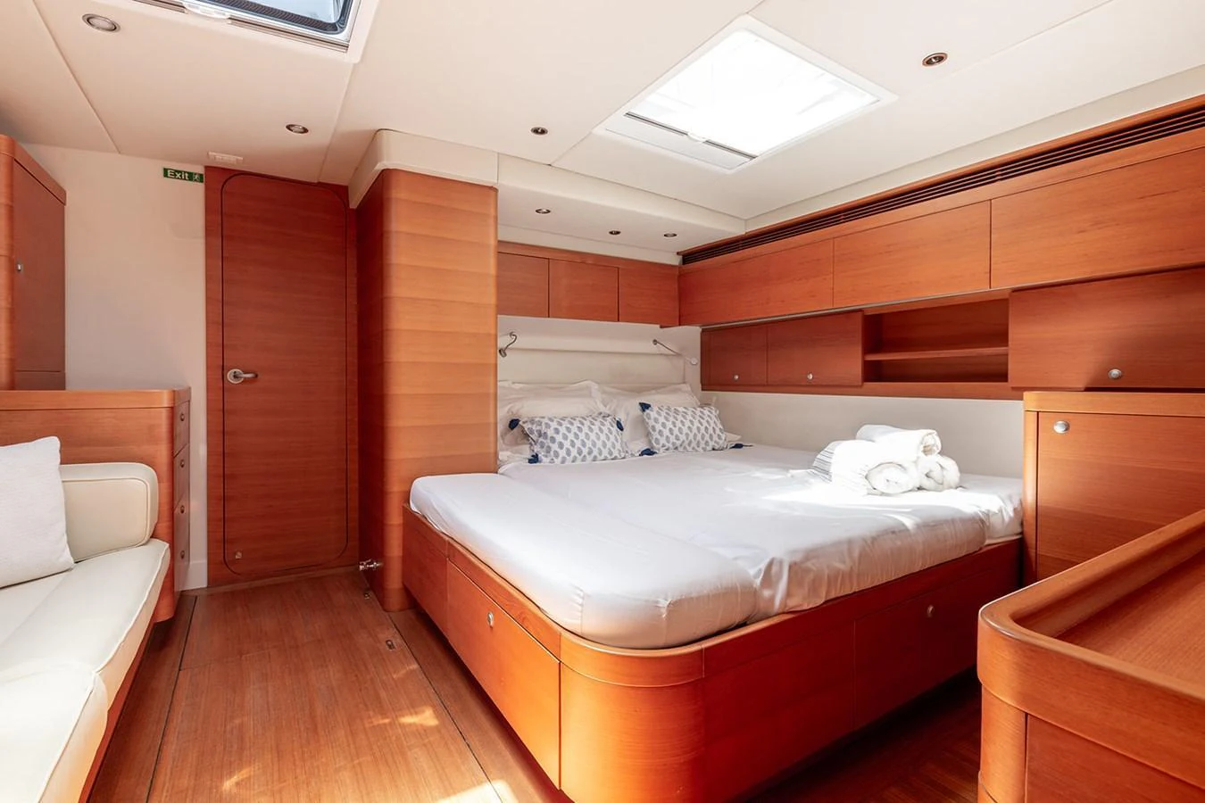 The master stateroom features a spacious bed with elegant wooden finishes and ample natural light. aboard CAIAROSSA Yacht for Sale