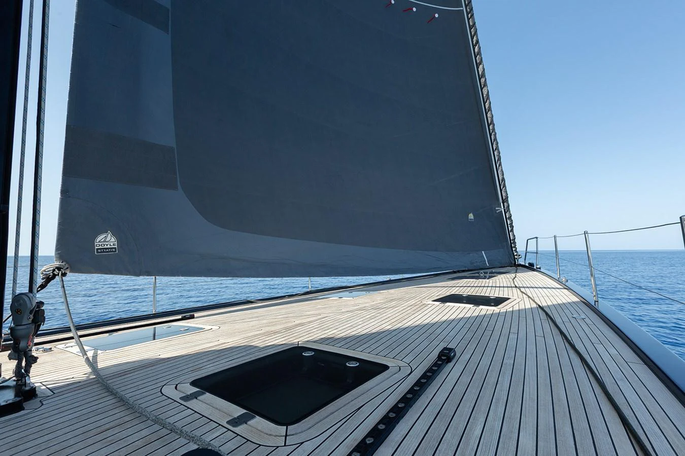 The yacht's deck features sleek, modern lines with a large sail and expansive open space. aboard CAIAROSSA Yacht for Sale