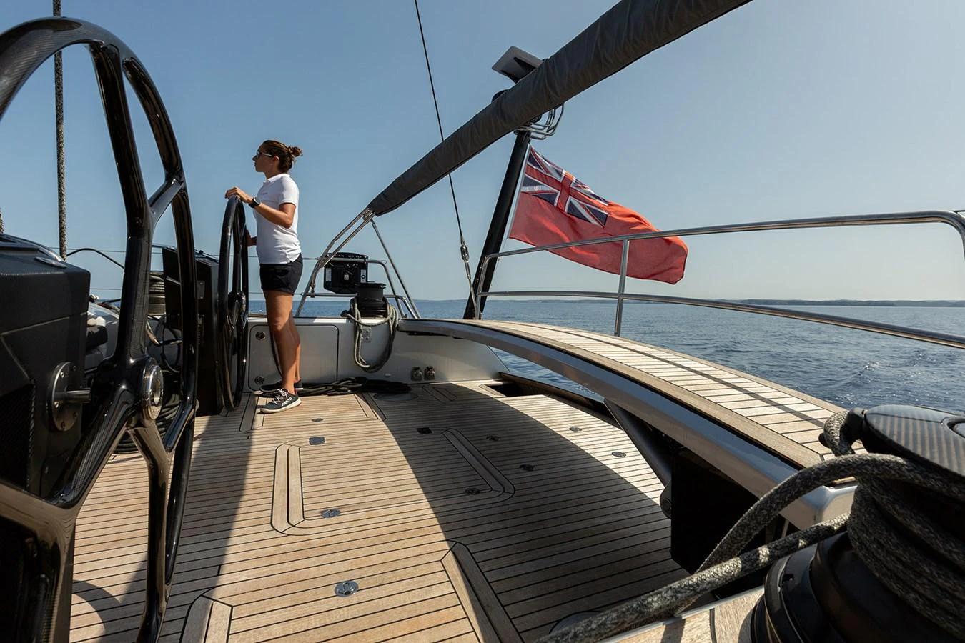 The yacht's deck offers a spacious and elegant area for navigation and relaxation, featuring a steering wheel and a view of the open sea. aboard CAIAROSSA Yacht for Sale
