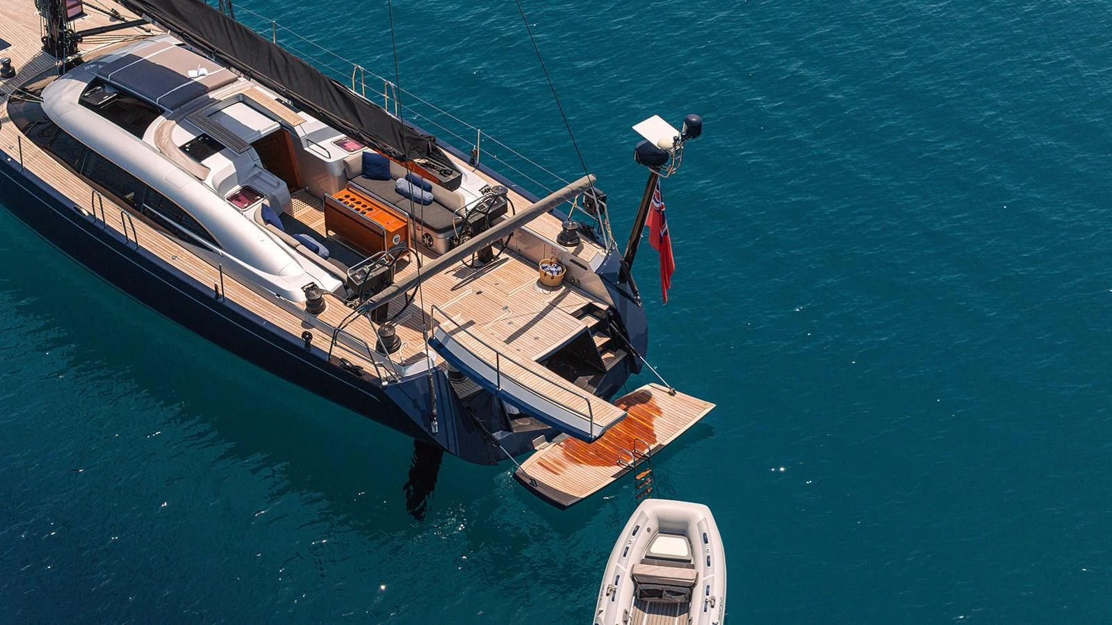 The yacht's aft deck features a swim platform and a tender floating nearby, showcasing its elegant design and functionality. aboard CAIAROSSA Yacht for Sale
